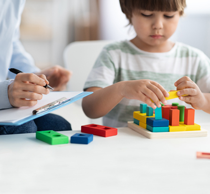 Weiterbildungen für Fachkräfte. Arbeitskreis Integration. Das Bild zeigt eine erwachsene Frau mit drei Kindern an einem Tisch. Die Kinder spielen.