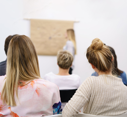Weiterbildungen für Fachkräfte. Arbeitskreis Integration. Das Bild zeigt eine erwachsene Frau mit drei Kindern an einem Tisch. Die Kinder spielen.