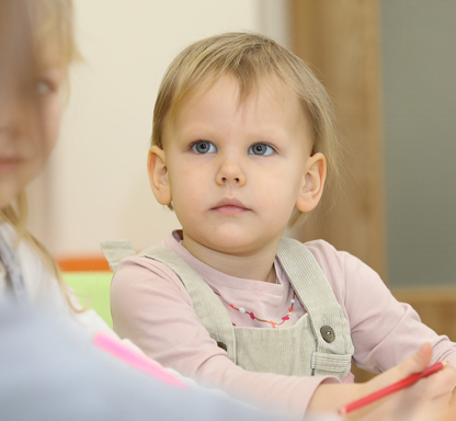 Offene Anlaufstelle bei BSL Kassel zur Frühförderung. Bild zeigt zwei Kinder, die an einem Tisch sitzen und sich anschauen.