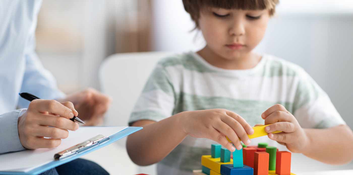 Kurse für Fachkräfte: Weiterbildung ICF-CY. Bild zeigt teilnehmende Gruppe von Personen von hinten. Im Hintergrund ist eine Frau zu sehen, die an einer Tafel steht und referiert.